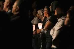 People holding candles in a dark setting.